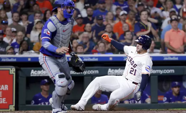 Houston Astros designated hitter Yainer Diaz, right, slides behind Texas Rangers catcher Kyle Higashioka, left, as he scores on the RBI single by Jesus Sanchez during the fourth inning of a baseball game Tuesday, Sept. 16, 2025, in Houston. (AP Photo/Michael Wyke)