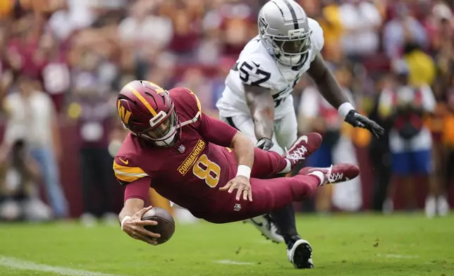 Washington Commanders quarterback Marcus Mariota (8) scores a touchdown as Las Vegas Raiders linebacker Germaine Pratt (57) defends during the first half of NFL football game Sunday, Sept. 21, 2025, in Landover, Md. (AP Photo/Stephanie Scarbrough)