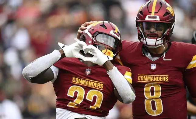 Washington Commanders running back Jacory Croskey-Merritt (22) celebrates with quarterback Marcus Mariota (8) after scoring a touchdown during the second half of NFL football game against the Las Vegas Raiders, Sunday, Sept. 21, 2025, in Landover, Md. (AP Photo/Nick Wass)