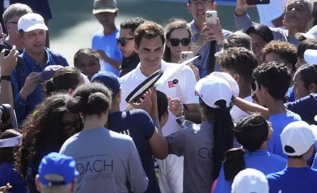 Co-creator of the Laver Cup Roger Federer, middle, signs autographs after hitting tennis balls to local youth tennis players during a court unveiling at John McLaren Park Tennis Courts before the Laver Cup tennis matches in San Francisco, Tuesday, Sept. 16, 2025. (AP Photo/Jeff Chiu)