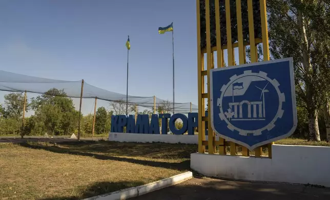 The Kramatorsk city sign and Ukrainian flags are seen next to the road covered with nets to protect cars from the enemy drones, Kramatorsk, Donetsk region, Ukraine, Friday, Sept.12, 2025. (AP Photo/Alex Babenko)
