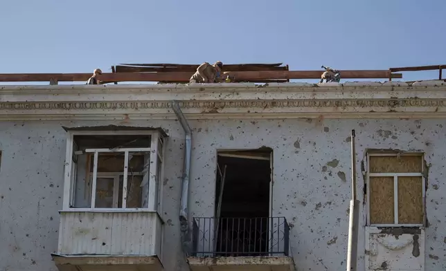 Men repair the roof of a multistory building damaged after a Russian missile hit the city center in Kramatorsk, Donetsk region, Ukraine, Friday, Sept. 12, 2025. (AP Photo/Alex Babenko)