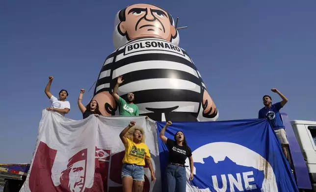 University students display an inflatable doll of Brazil's former President Jair Bolsonaro wearing prisoner garb in Brasilia, Brazil, Friday, Sept. 12, 2025, the morning after the Supreme Court convicted and sentenced him to prison for attempting a coup to remain in office despite his 2022 electoral defeat. (AP Photo/Eraldo Peres)