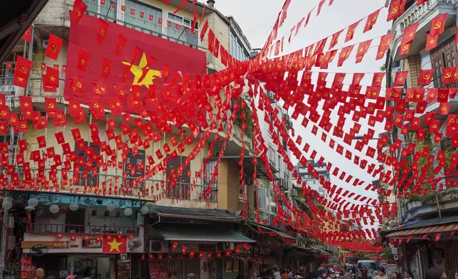 Vietnamese and communist flags hang from balconies across streets in the old quarter of Hanoi, Vietnam, Monday, Sept. 1, 2025. (AP Photo/Vincent Thian)