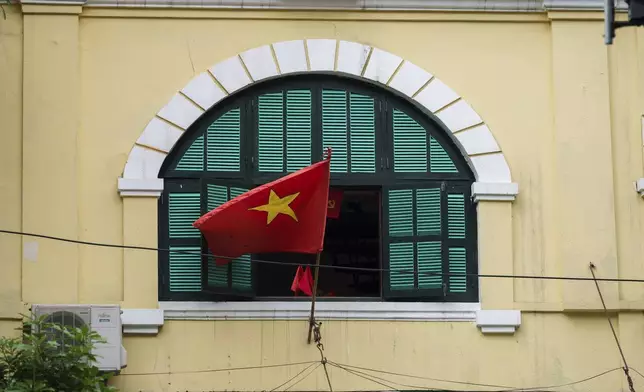 A Vietnamese national flag flies outside a window in the old quarter of Hanoi, Vietnam, Sunday, Aug. 31, 2025. (AP Photo/Vincent Thian)
