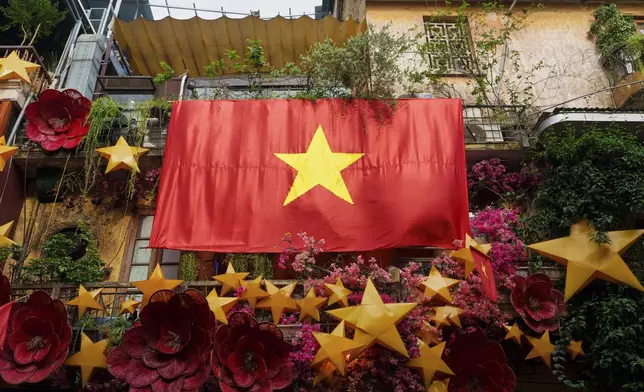 A giant Vietnamese national flag hangs from a balcony in the old quarter of Hanoi, Vietnam, Monday, Sept. 1, 2025. (AP Photo/Vincent Thian)