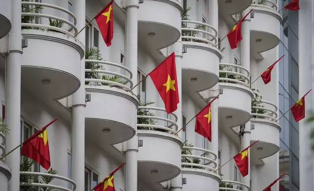Vietnamese national flags fly from balconies of a hotel in Hanoi, Vietnam, Monday, Sept. 1, 2025. (AP Photo/Vincent Thian)