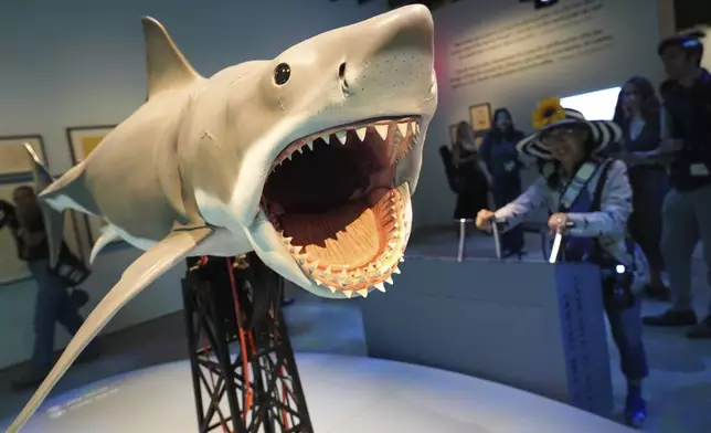 An interactive scale replica based on the shark from the 1975 film "Jaws" is controlled by a visitor during the "Jaws: The Exhibition" press preview on Wednesday, Sept. 10, 2025, at the Academy Museum of Motion Pictures in Los Angeles. (AP Photo/Chris Pizzello)