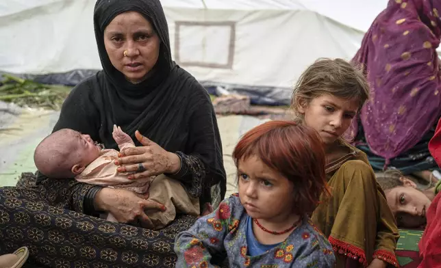 A woman and her children, survivors of Sunday night's 6.0-magnitude earthquake, wait for assistance in the village of Wadir, Kunar province, eastern Afghanistan, Tuesday, Sept. 2, 2025. (AP Photo/Nava Jamshidi)