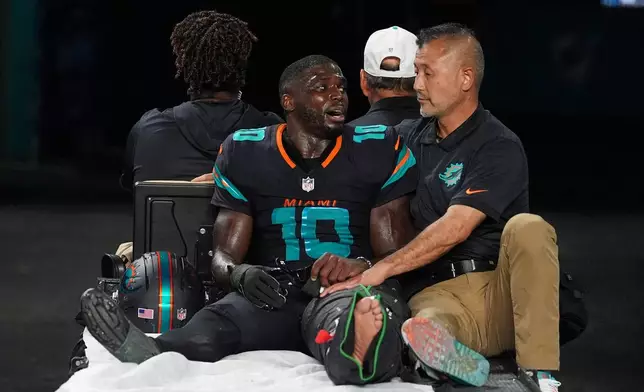 Miami Dolphins wide receiver Tyreek Hill (10) talks with a staff member as he is carted off the field after suffering an unknown lower leg injury in the second half of an NFL football game against the New York Jets, Monday, Sept. 29, 2025, in Miami Gardens, Fla. (AP Photo/Rebecca Blackwell)