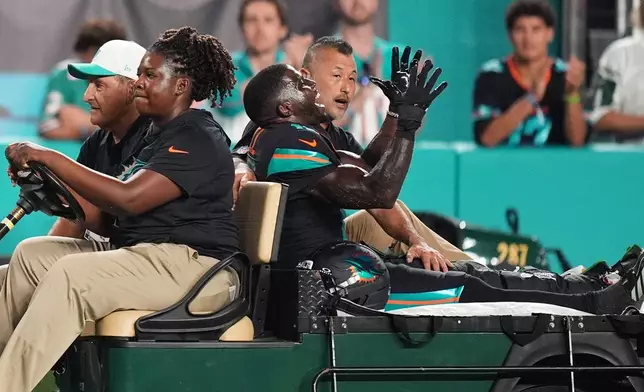 Miami Dolphins wide receiver Tyreek Hill, right font, puts his arms up as he is carted off the field after suffering an unknown lower leg injury in the second half of an NFL football game against the New York Jets, Monday, Sept. 29, 2025, in Miami Gardens, Fla. (AP Photo/Rebecca Blackwell)