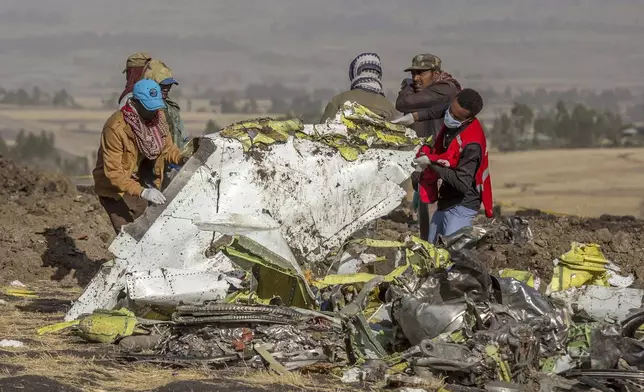 FILE - Workers recover debris at the scene of an Ethiopian Airlines Boeing Max plane crash on March 11, 2019, outside of Addis Ababa, Ethiopia. (AP Photo/Mulugeta Ayene, File)'
