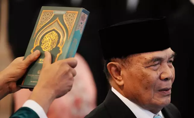 An Islamic cleric holds a holy book of Quran over the head of the newly-appointed Coordinating Minister for Political and Security Affairs Djamari Chaniago during the swearing-in ceremony at the presidential palace in Jakarta, Indonesia , Wednesday, Sept. 17, 2025. (AP Photo/Achmad Ibrahim)