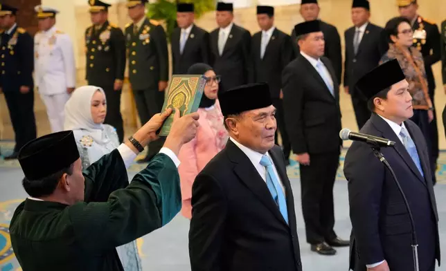 An Islamic cleric holds a holy book of Quran over the head of the newly-appointed Coordinating Minister for Political and Security Affairs Djamari Chaniago, center, and minister of youth and sports Erick Thohir, right, during a swearing-in ceremony at the presidential palace in Jakarta, Indonesia, Wednesday, Sept. 17, 2025. (AP Photo/Achmad Ibrahim)