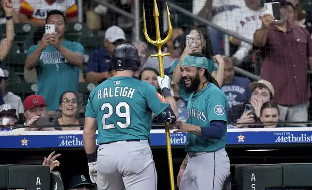Seattle Mariners' J.P. Crawford, right, presents Cal Raleigh a trident after Raleigh hit a two-run home run against the Houston Astros during the second inning of a baseball game Sunday, Sept. 21, 2025, in Houston. (AP Photo/Eric Christian Smith)