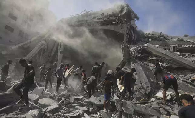 Palestinians search for wood to sell or use for cooking amid the rubble of a building hit by an Israeli strike in Gaza City, Sunday, Sept. 14, 2025. (AP Photo/Yousef Al Zanoun)