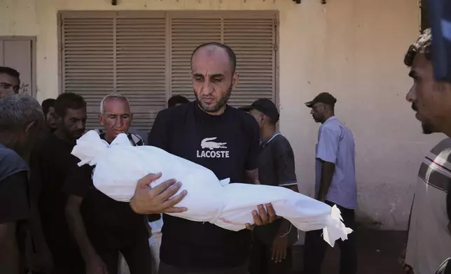 A man carries the body of 3-year-old Palestinian child Nour Abu Ouda, killed in an Israeli airstrike on the Gaza Strip, at Al-Aqsa Hospital in Deir al-Balah, Sunday, Sept. 14, 2025. (AP Photo/Abdel Kareem Hana)