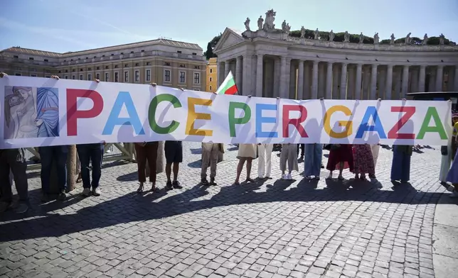 People hold a banner reading "Peace for Gaza' as Pope Leo XIV recites the Angelus noon prayer from the window of his studio overlooking St.Peter's Square, at the Vatican, Sunday, Sept. 21, 2025. (AP Photo/Andrew Medichini)