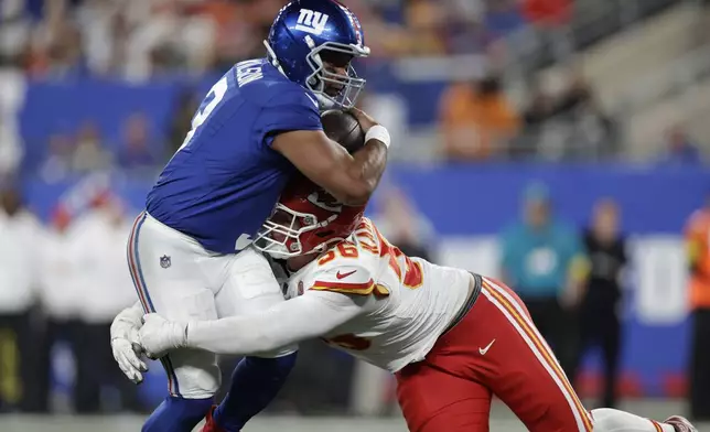 New York Giants quarterback Russell Wilson, left, runs with the ball as Kansas City Chiefs defensive end George Karlaftis (56) defends during the second half of an NFL football game Sunday, Sept. 21, 2025, in East Rutherford, N.J. (AP Photo/Adam Hunger)
