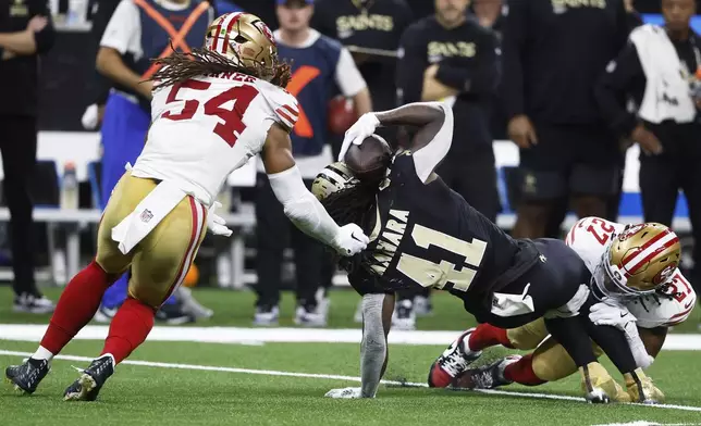 New Orleans Saints running back Alvin Kamara (41) is brought down by San Francisco 49ers safety Ji'Ayir Brown, right, before fumbling the ball, which was recovered by linebacker Fred Warner (54), during the second half of an NFL football game in New Orleans, Sunday, Sept. 14, 2025. (AP Photo/Butch Dill)