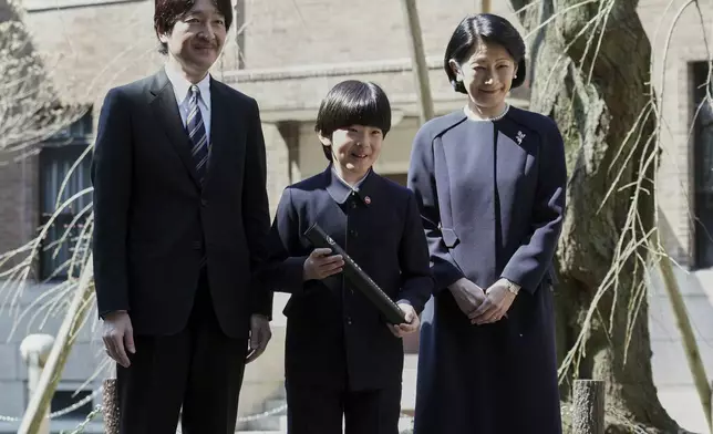 FILE- Japan's Prince Hisahito, center, accompanied by his parents Prince Akishino and Princess Kiko pose for media after his graduation ceremony of a primary school affiliated with Ochanomizu University in Tokyo Friday, March 15, 2019. (AP Photo/Eugene Hoshiko, Pool)