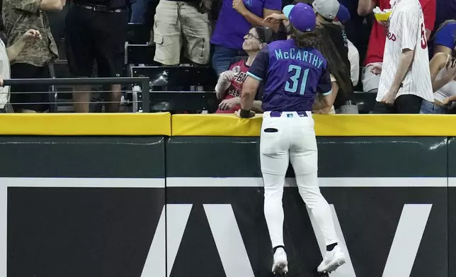 Arizona Diamondbacks left fielder Jake McCarthy leaps in vain for a home run hit by Philadelphia Phillies' Harrison Bader during the fifth inning of a baseball game Friday, Sept. 19, 2025, in Phoenix. (AP Photo/Ross D. Franklin)