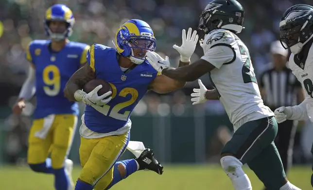 Los Angeles Rams running back Blake Corum (22) runs with the ball as Philadelphia Eagles cornerback Quinyon Mitchell, right, defends during the second half of an NFL football game Sunday, Sept. 21, 2025, in Philadelphia. (AP Photo/Matt Rourke)