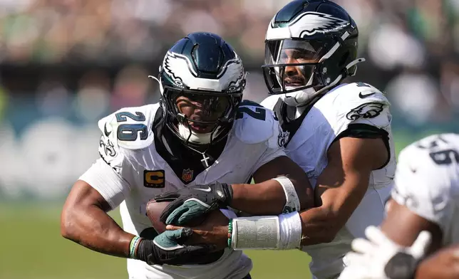 Philadelphia Eagles quarterback Jalen Hurts (1) hands off to running back Saquon Barkley (26) during the second half of an NFL football game against the Los Angeles Rams Sunday, Sept. 21, 2025, in Philadelphia. (AP Photo/Chris Szagola)