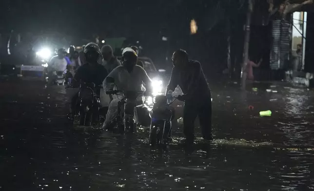 Motorcycles move through a flooded road caused by heavy rain in Lahore, Pakistan, Monday, Sept. 8, 2025. (AP Photo/K.M. Chaudary)