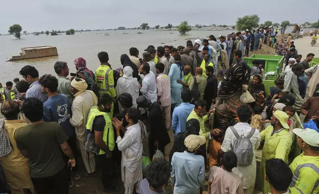 Volunteers help villagers on the higher ground after they are evacuated by rescue workers from a flooded area following raising water level in rivers, in Jalalpur Pirwala, in Multan district, Pakistan, Monday, Sept. 8, 2025. (AP Photo/Asim Tanveer)