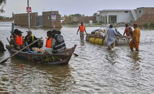 A rescue boat move past villagers pushing a makeshift raft following raising water level in rivers, in Jalalpur Pirwala, in Multan district, Pakistan, Monday, Sept. 8, 2025. (AP Photo/Asim Tanveer)