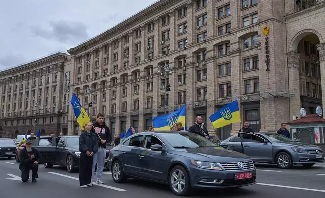 Motorists stop their cars to pay respect to a soldier who was killed in Russia-Ukraine war as a vehicle with his body drives along the city main Khreshchatyk Street in Kyiv, Ukraine, Wednesday, Sept. 24, 2025. (AP Photo/Efrem Lukatsky)