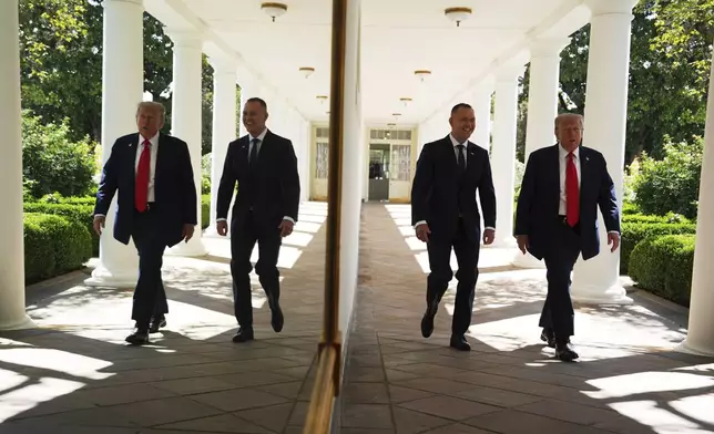 President Donald Trump and Polish President Karol Nawrocki, right, are seen reflected in the wall along the colonnade, as they walk toward an Oval Office meeting, at the White House, Wednesday, Sept. 3, 2025, in Washington. (AP Photo/Evan Vucci)
