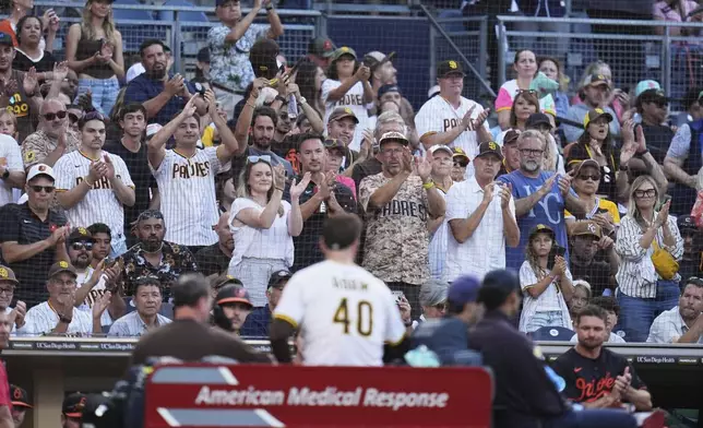 Fans applaud as San Diego Padres relief pitcher Jason Adam leaves in a cart after falling with an injury during the seventh inning of a baseball game against the Baltimore Orioles Monday, Sept. 1, 2025, in San Diego. (AP Photo/Gregory Bull)