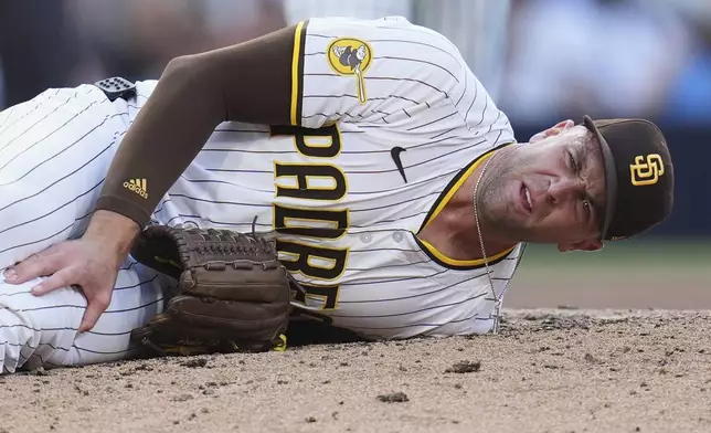 San Diego Padres relief pitcher Jason Adam holds his leg after falling with an injury during the seventh inning of a baseball game against the Baltimore Orioles Monday, Sept. 1, 2025, in San Diego. (AP Photo/Gregory Bull)