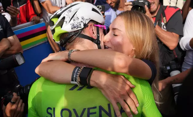 Slovenia's Tadej Pogacar celebrates with his partner Urska Zigart after winning the men's Elite road race, at the road cycling World Championships in Kigali, Rwanda, Sunday, Sept. 28, 2025. (AP Photo/Jerome Delay)