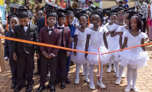 Children wait to walk down the aisle at their kindergarten graduation, Saturday, Nov. 23, 2024, in Kampala, Uganda. (AP Photo/David Goldman)