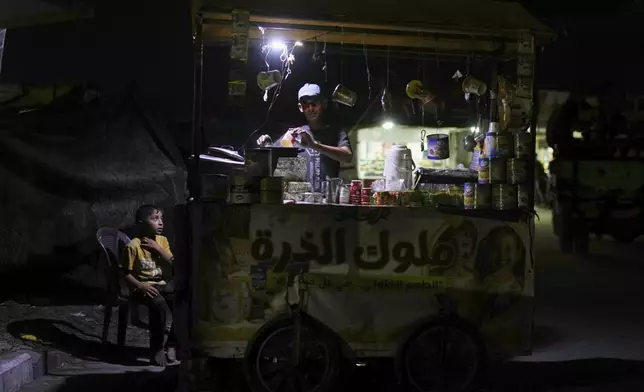 A Palestinian boy looks at a street vendor cooking corn near the beachfront at a tent camp for displaced people in the Gaza City port, Tuesday, Sept. 2, 2025. (AP Photo/Jehad Alshrafi)