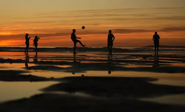 Youngsters play with a ball at the sea shore as the sun sets in Conil de la Frontera beach, southern Spain, Wednesday, Sept. 3, 2025. (AP Photo/Francisco Seco)