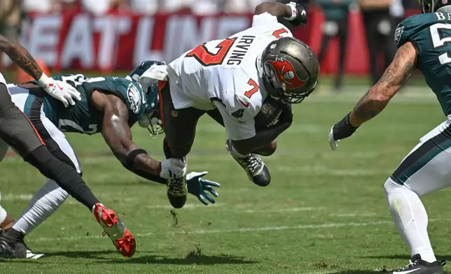Tampa Bay Buccaneers running back Bucky Irving (7) is tripped up by Philadelphia Eagles safety Andrew Mukuba (24) during the first half of an NFL football game Sunday, Sept. 28, 2025, in Tampa, Fla. (AP Photo/Jason Behnken)