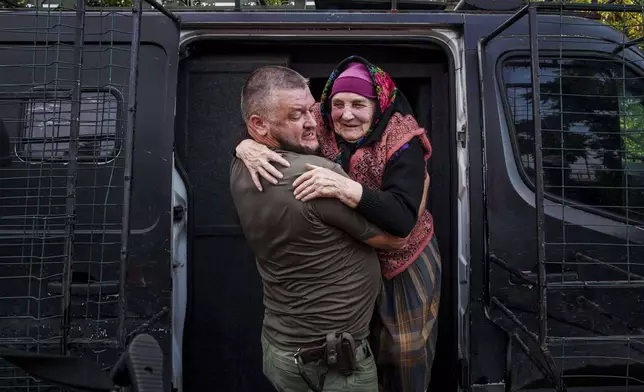 A police officer helps Maria Hodus, 90, to come out from a van during an evacuation from Kostiantynivka, Ukraine, Tuesday, Sept. 2, 2025. (AP Photo/Evgeniy Maloletka)