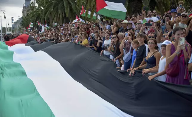 People hold Palestinian flags as they bid farewell to activists setting sail on their boats to join a civilian flotilla bound for Gaza, with the aim of breaking the Israeli blockade and delivering humanitarian aid, in Barcelona, Spain, on Sunday, August 31, 2025. (AP Photo/Emilio Morenatti)