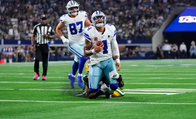 Dallas Cowboys quarterback Dak Prescott (4) is stopped as he carries the ball by Green Bay Packers defensive end Micah Parsons, rear, in overtime of an NFL football game Sunday, Sept. 28, 2025, in Arlington, Texas. (AP Photo/Jeffrey McWhorter)