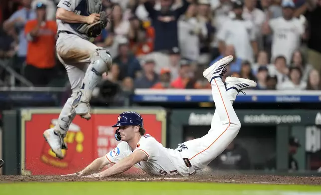 Houston Astros' Jacob Melton dives home to score a run on Yordan Alvarez's RBI single as New York Yankees catcher Austin Wells jumps up to try to defend the plate during the seventh inning of a baseball game Wednesday, Sept. 3, 2025, in Houston. (AP Photo/Karen Warren)