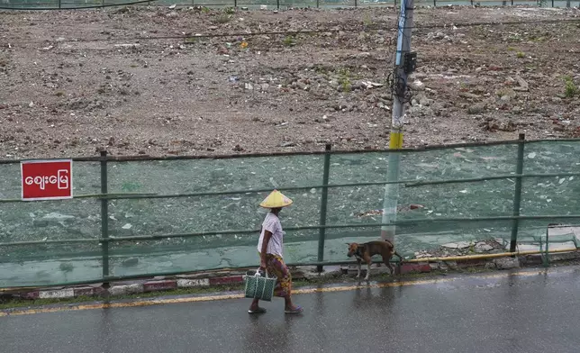 A woman walks past an empty field that once was a local market, destroyed in the March 28 earthquake in Naypyitaw, Myanmar, Tuesday, Aug. 26, 2025. (AP Photo/Aung Shine Oo)