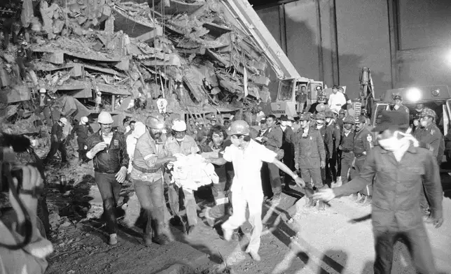FILE - Emergency workers carry hospital patient Rubalcada Pena after rescuing him from the rubble of Mexico City's Juarez Hospital, which was destroyed by an earthquake, Sept. 26, 1985. (AP Photo/Jack Smith, File)