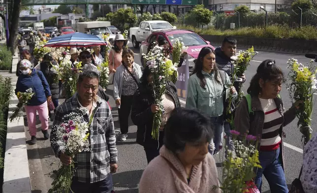 People bring flowers to site where seamstress died inside a textile plant that collapsed in the 1985 earthquake on the 40th anniversary of the quake in the Obrera neighborhood of Mexico City, Friday, Sept. 19, 2025. (AP Photo/Jon Orbach)