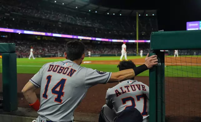 Houston Astros' Mauricio Dubon (14) and Jose Altuve (27) watch from the dugout during the third inning of a baseball game against the Los Angeles Angels Saturday, Sept. 27, 2025, in Anaheim, Calif. (AP Photo/Jae C. Hong)
