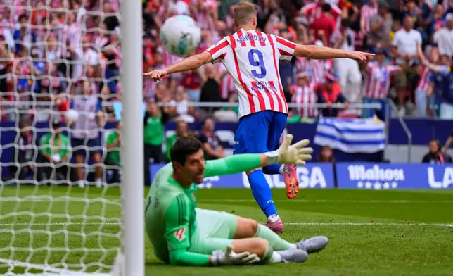 Atletico Madrid's Alexander Sorloth, top, celebrates after scoring his side's second goal past Real Madrid's goalkeeper Thibaut Courtois during the Spanish La Liga soccer match between Atletico Madrid and Real Madrid at Metropolitano stadium, in Madrid, Spain, Saturday, Sept. 27, 2025. (AP Photo/Manu Fernandez)