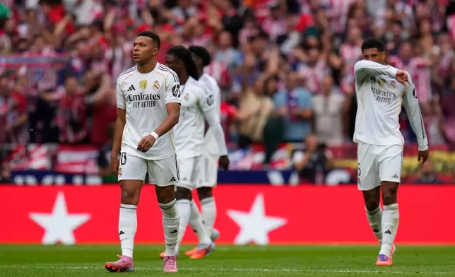 Real Madrid players walk at the pitch after Atletico Madrid's Julian Alvarez scored his side's fourth goal during the Spanish La Liga soccer match between Atletico Madrid and Real Madrid at Metropolitano stadium, in Madrid, Spain, Saturday, Sept. 27, 2025. (AP Photo/Manu Fernandez)